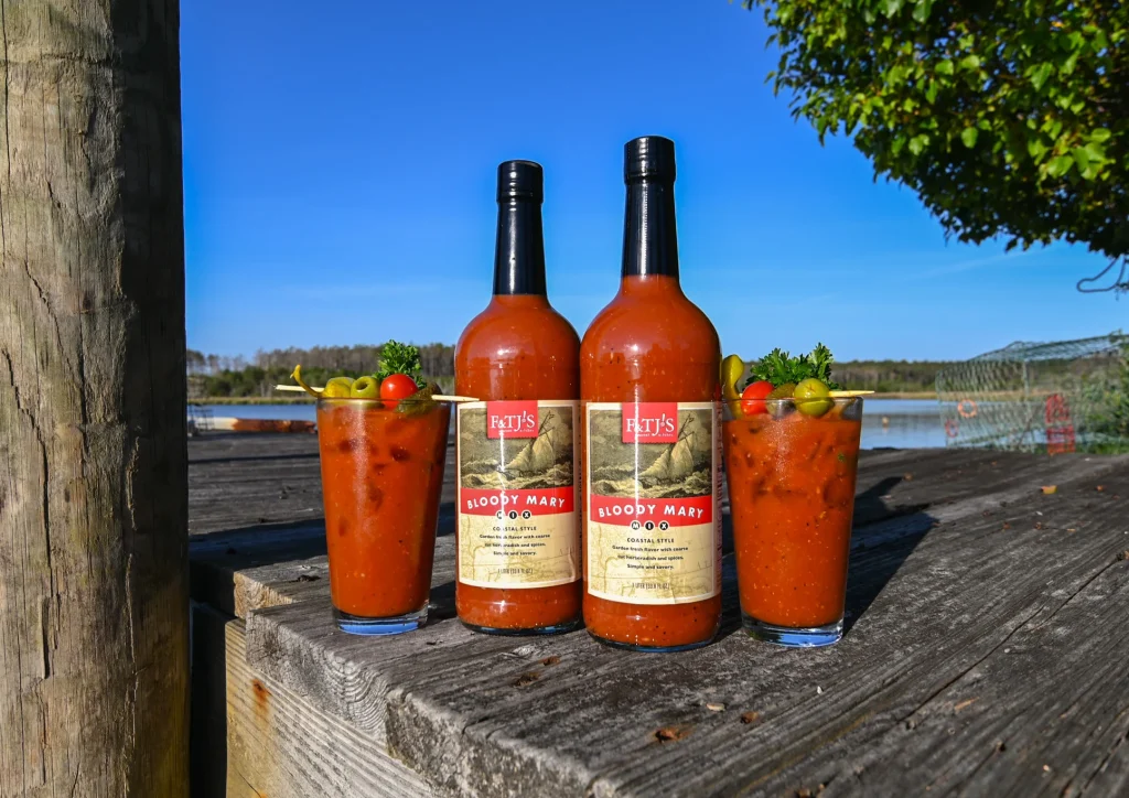 Two Bloody Mary drinks and F&TJ’s bottle arranged on a dock in coastal North Carolina